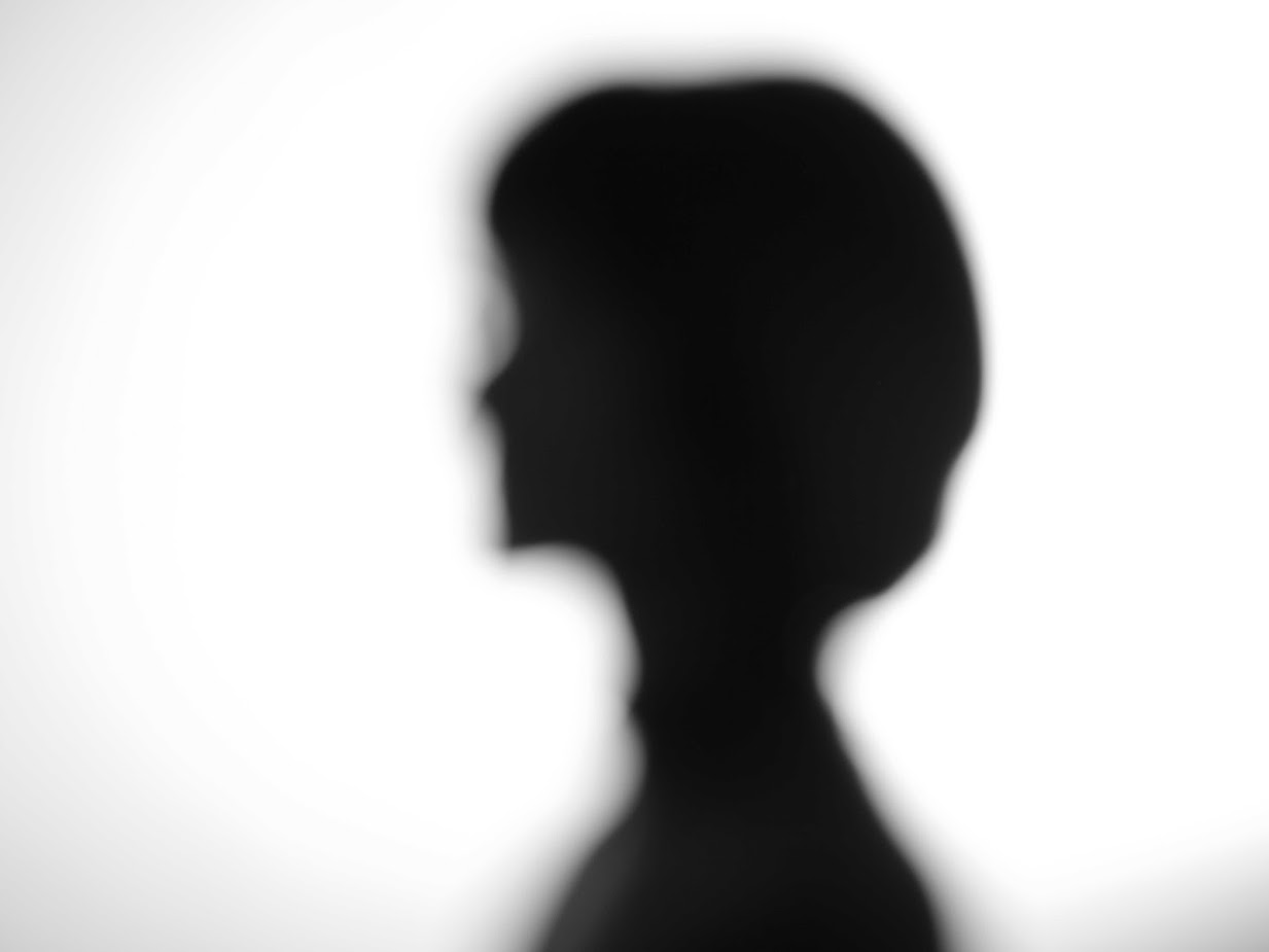 Photo in black and white of the Shilouette of a woman out of focus on a white background