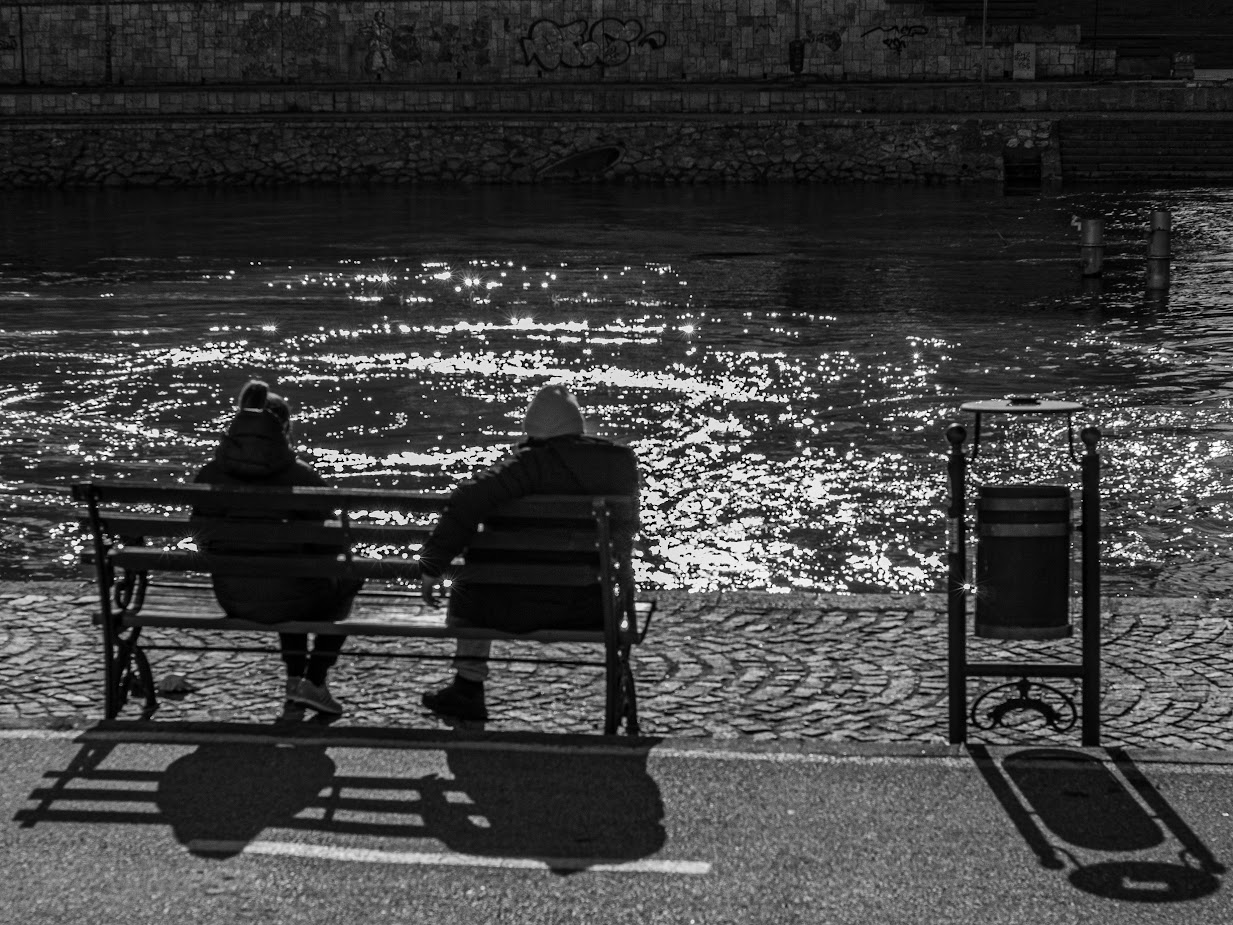 Photo of two people sit by a river
